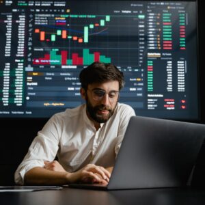 Male analyst studies cryptocurrency trends at a workstation with multiple displays showing market data.